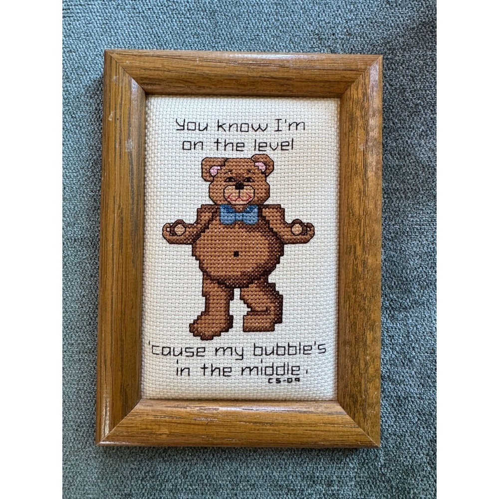 Vintage cross-stitch embroidery featuring a teddy bear with a blue bow tie.